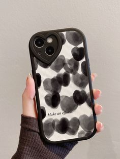 a person holding up a cell phone case with black and white hearts on the back