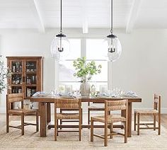 a dining room table and chairs in front of a large window with an area rug