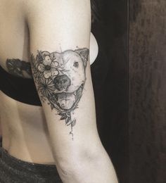 a woman's arm with a dog and flowers tattooed on the left side of her arm