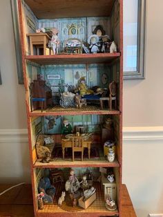 a doll house with furniture and dolls on the shelves