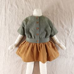 the doll is wearing a green jacket and brown dress with white tights on it's legs