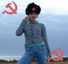 a woman wearing jeans and a hat is talking on her cell phone while standing in a field