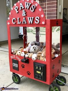 a red claw game with stuffed animals in it and paws and claws written on the front