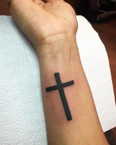 a person with a cross tattoo on their wrist