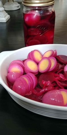 a bowl filled with pickled up radishes next to a jar of jelly