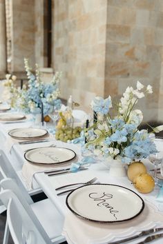 the table is set with white and blue flowers