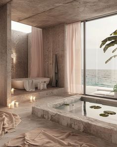 a bath room with a large window next to the water and candles on the floor