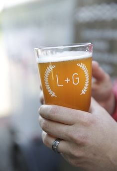 a close up of a person holding a glass of beer with the number 16 on it