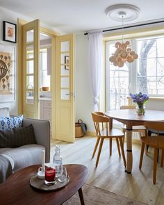 a living room filled with furniture and a dining table next to a large open window