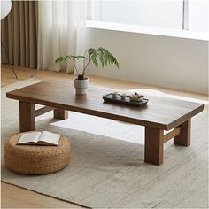 a living room with a coffee table and potted plant on the rug in front of it