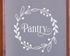 a wooden frame with the word pantry painted on it and a wreath in the center