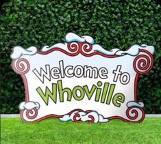 a welcome sign sitting in front of a green wall with bushes behind it and the words'welcome to whowvillee'written on it