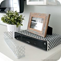 a black and white photo frame sitting on top of a shelf next to a potted plant