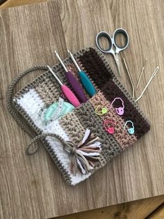 a crocheted purse with scissors and other crafting supplies on it sitting on a wooden table