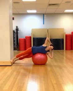 a woman is doing exercises on an exercise ball in a gym with red yoga mats