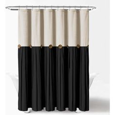 a black and white shower curtain with gold buttons on the bottom, hanging from a metal rod