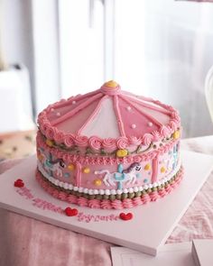 a birthday cake with pink frosting and an umbrella decoration on the top is sitting on a table