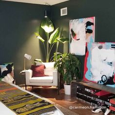 a living room filled with furniture and paintings on the wall next to a white couch