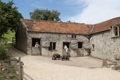 an old stone building with three pigs in the driveway