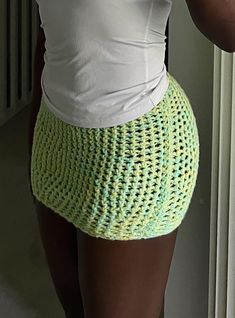 a woman taking a selfie with her cell phone and wearing a green knitted skirt