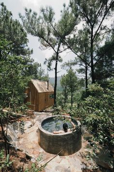 an outdoor hot tub surrounded by trees with a cabin in the backgroung