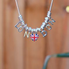 London and Union Jack heart charm silver tone coronation pendant necklace, with red, white and blue hand finished enamel.    Designed by us, at our London office. This beautiful necklace celebrates the best of British. Wear a Union Jack with pride for any other occasion you fancy. Necklace: (Drop) 48.5cm Each item is presented on a recycled paper gift card (as shown), packed in biodegradable bags and then placed in an eco-friendly envelope (also shown). Orders are sent in 100% recyclable paper padded envelopes, to keep the jewellery safe during delivery.   The pendant is on a 41cm chain, with 7.5cm extension chain and lobster clasp. This is just one design from our range of Union Jack jewellery and scarves.  Shop more styles: https://www.etsy.com/uk/shop/ATLondonJewels?ref=shop_sugg_market London Necklace, Heart Charm Necklace, Best Of British, Fancy Necklace, London Office, Mens Jewelry Necklace, Jewelry Safe, Blue Hand, Union Jack