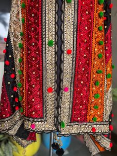 a red and black jacket with pom poms hanging from it's sides