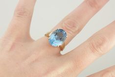 Although bold, his vintage cocktail ring is perfectly balanced in size and width, and so not overwhelming on the finger. We've set this beauty with a cushion cut blue topaz in the perfect shade of London Blue! This stone has a fancy cut that has great flash and glitter, which seems to come from deep within the stone. Metal: 10K Yellow Gold Gem: Blue Topaz 9.92 Carats Gem Measurements: 11.9 x 15.8 mm, Oval Ring Size: 6.25 Marks: "10K MP" Stamped on the inside band Blue Statement Ring, Topaz Cocktail Ring, Vintage Cocktail Ring, Oval Ring, Oval Rings, Vintage Cocktail, Ring Blue, London Blue, Blue Rings