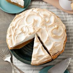 a cake with white frosting sitting on top of a table next to plates and utensils