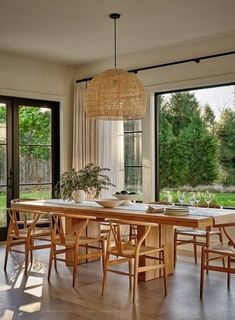 the dining room table is surrounded by wooden chairs and an area with large windows that look out onto trees