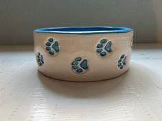 This medium size pet bowl was handmade on the pottery wheel with a smooth white clay and then pressed with this adorable trail of paw prints all the way around it. It is close to 7 inches wide. All blue inside and each paw print hand painted the matching sky blue. They make an excellent water bowl, food bowl or even treats! Also check out the personalized option in my shop! Feel free to message me with any questions or concerns. Dog Pottery Ideas, Dog Bowl Painting Ideas, Pottery Painting Dog Bowl, Pottery Bowls Painting Ideas, Clay Cat Bowl, Cat Bowl Pottery, Clay Dog Bowl, Pottery Beginners, Pottery Dog Bowl