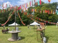 there are many tents set up in the grass with flags hanging from it's poles