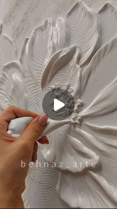 someone is painting a flower with white paint on the side of a wallpapered piece