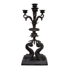 a black candle holder with three candles on it's sides and an ornate design