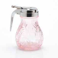 a pink glass pitcher with a silver lid