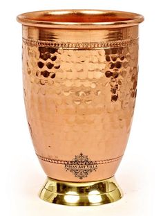 a large metal cup sitting on top of a gold plated stand with an ornate design