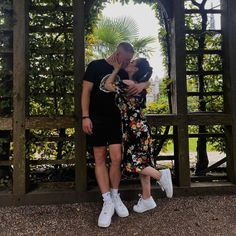 a man and woman standing in front of a gazebo with their arms around each other