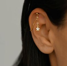 a close up of a person's ear with a star and chain attached to it