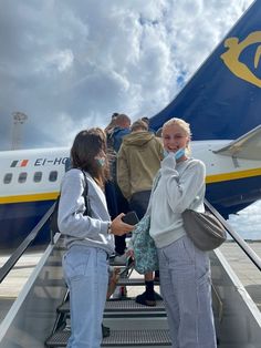 two women talking on the phone as they board an airplane with passengers walking up and down stairs