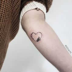 a woman's arm with a heart and paw tattoo on it