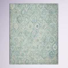 a blue and white area rug with an intricate design on the bottom, in front of a gray wall