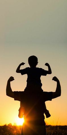 the silhouette of a person with their arms in the air, as the sun sets behind them