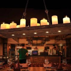 a chandelier with lit candles hanging from it's ceiling in a restaurant