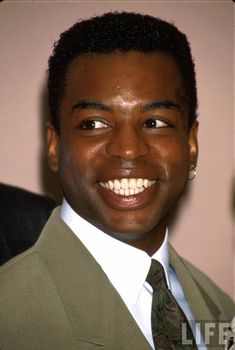 a close up of a person wearing a suit and tie with a smile on his face