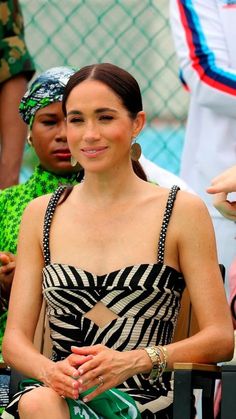 a woman in a zebra print dress sitting next to other people at a tennis match