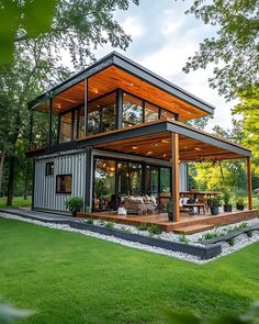 a house made out of shipping containers in the middle of a field with grass and trees