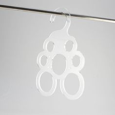 a pair of white circular earrings hanging from a metal hook on a clothes line against a gray background