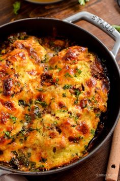 an omelet with cheese and herbs in a skillet on a wooden table