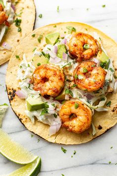 two shrimp tacos with lime wedges on the side