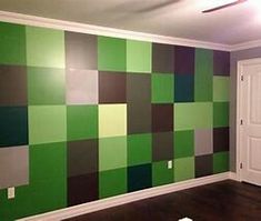 an empty room with green and brown squares painted on the wall, in front of a white door